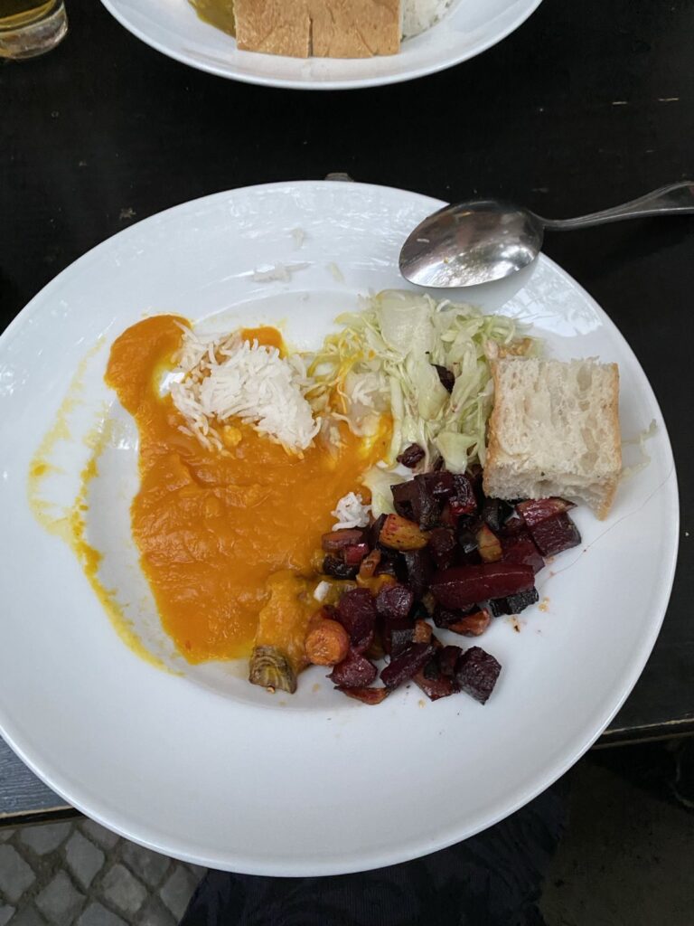Leckeres Küfa Essen auf einem weißen Teller: Kürbissuppe mit Reis und Rote Bete Salat.